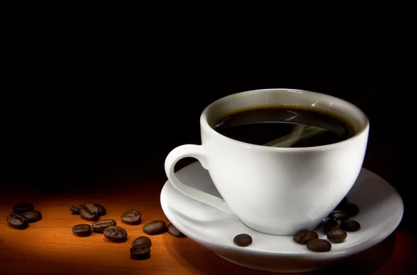 Xícara de café e feijão na textura de madeira — Fotografia de Stock