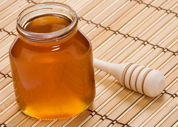 Pot of honey and wooden stick — Stock Photo, Image