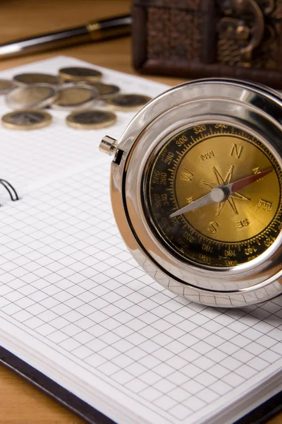 Kompas, pióro i monety na notebooka — Zdjęcie stockowe