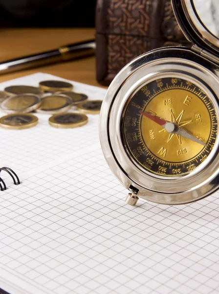 Kompas, zlaté mince a pera na notebook — Stock fotografie