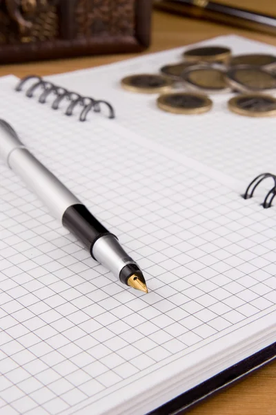 Pen and coin on notebook — Stock Photo, Image