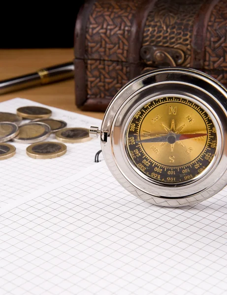 Kompass, penna och mynt på anteckningsboken — Stockfoto