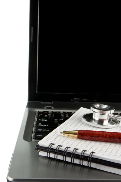 Stethoscope and pen at notebook laptop — Stockfoto