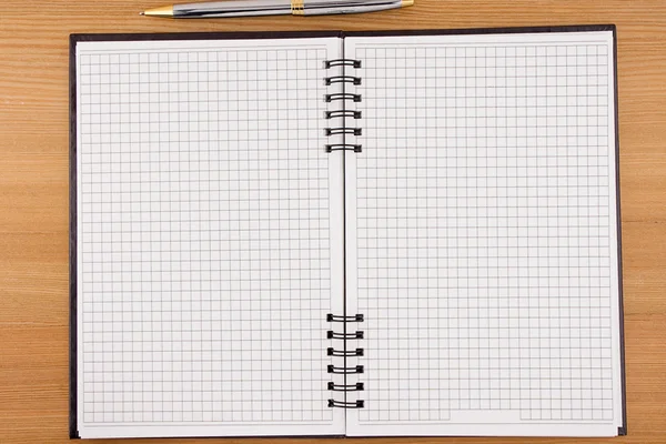 Bolígrafo y cuaderno comprobado sobre madera — Foto de Stock