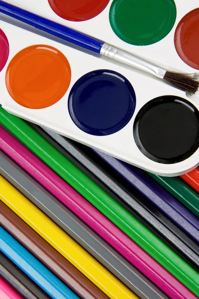 Paleta de pintores y pincel sobre lápices —  Fotos de Stock