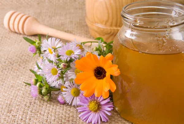 Honey in glass pot on sacking — Stock Photo, Image