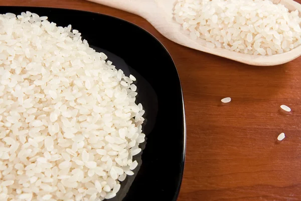 Reis und schwarzer Teller mit Kochlöffel — Stockfoto
