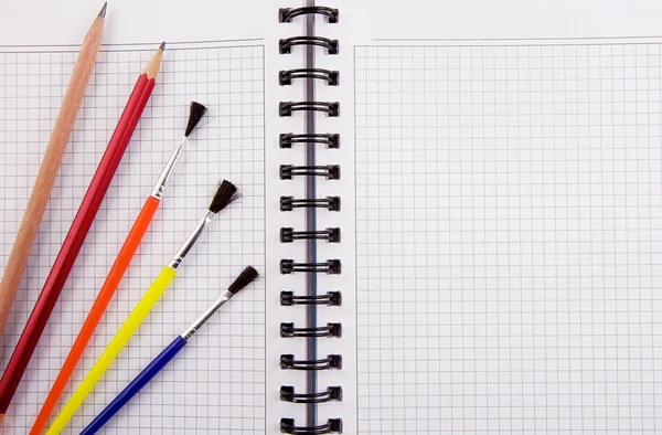 Borstel en potloden op notebook Stockfoto