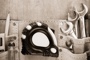 Tools in construction belt on wooden background