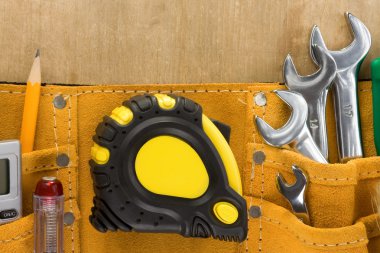 Tools in construction belt on wooden background
