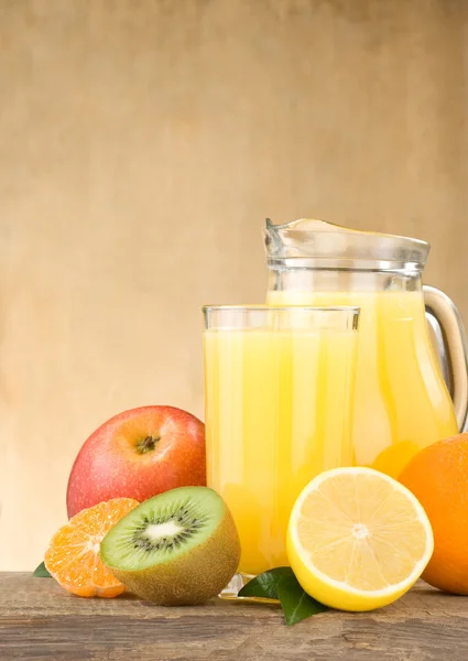 Fresh fruits juice in glass and slices on wood — Stock Photo, Image