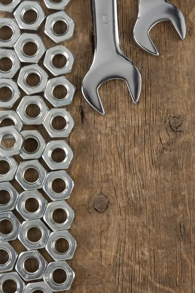 Metalowe nakrętki i narzędzie klucza na tle drewna — Zdjęcie stockowe