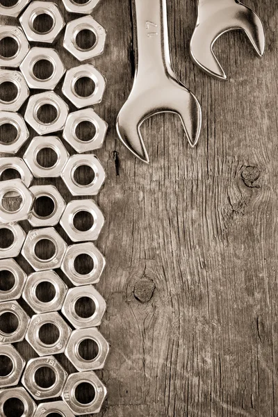 Porcas de metal e ferramenta chave no fundo de madeira — Fotografia de Stock