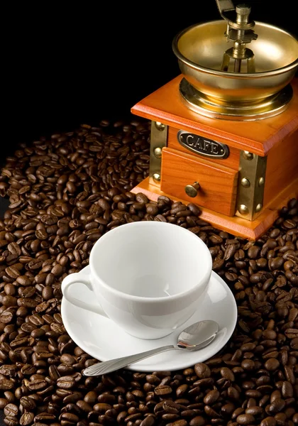 Cup of coffee and grinder on beans — Stock Photo, Image