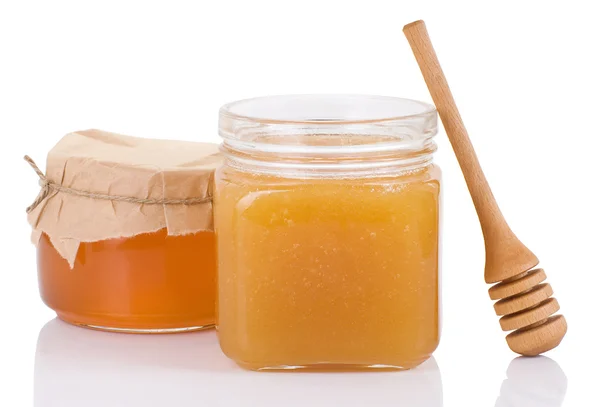Pentola piena di miele e bastone isolato su bianco — Foto Stock