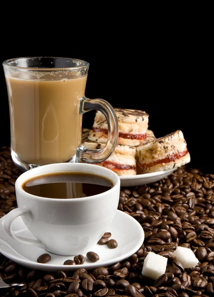 Xícara cheia de café e bolos de feijão isolado em preto — Fotografia de Stock