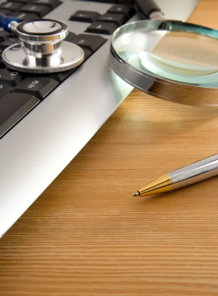 Estetoscópio e teclado com caneta sobre madeira — Fotografia de Stock