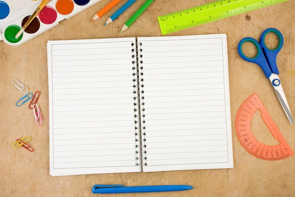 Accesorios escolares y cuaderno comprobado sobre madera — Foto de Stock