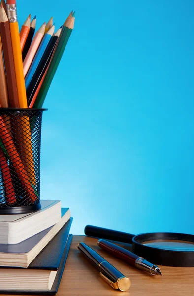 Booksa i pióra z ołówkiem w uchwycie na niebieskim tle — Zdjęcie stockowe