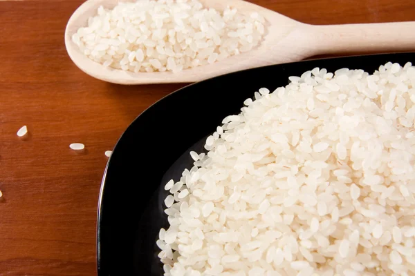 Рис и тарелка с ложкой на столе — стоковое фото