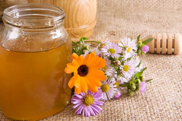 Honeycomb, flowers and honey in glass on sack — Stock Photo, Image