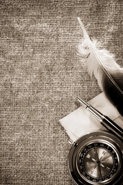 Brújula y pluma de tinta sobre fondo antiguo saco vintage —  Fotos de Stock