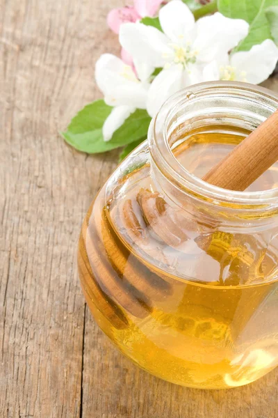 Honey in glass jar and stick — Stock Photo, Image