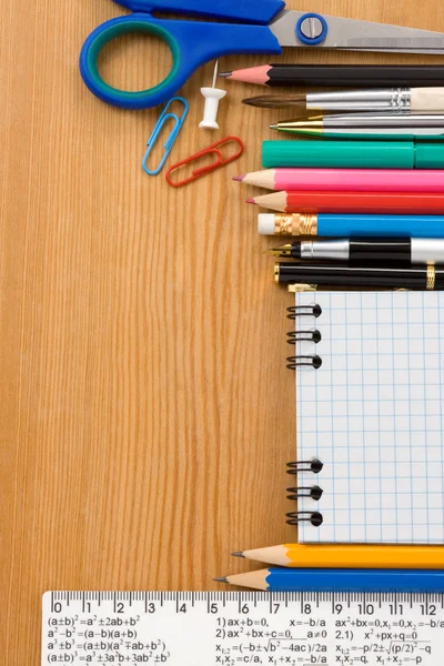 School supplies and checked notebook on wood — Stockfoto