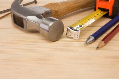 Hammer, tape measure, nail and pencil on wood clipart