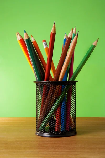Cestino portapenne pieno di matite colorate sul tavolo — Foto Stock