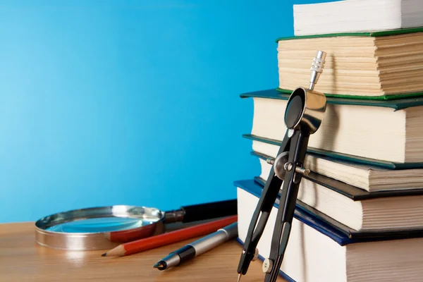 Pen, big pile of books and magnifying glass — Stock Photo, Image