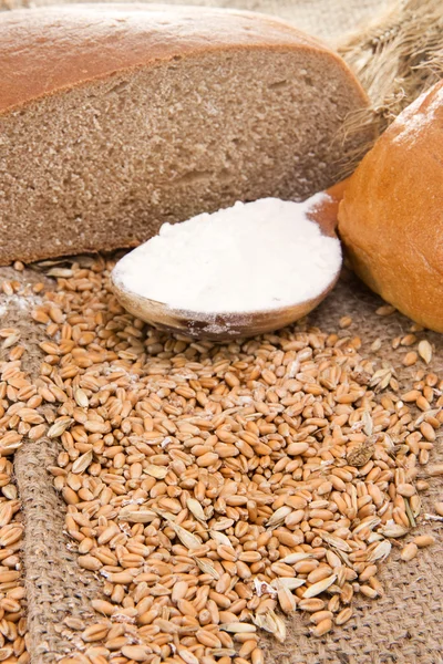 Хлеб и деревянная ложка на зерне — стоковое фото