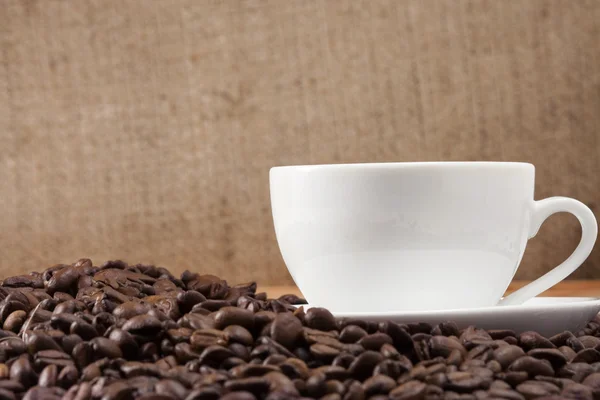 Kopp kaffe på bönor nära säck — Stockfoto
