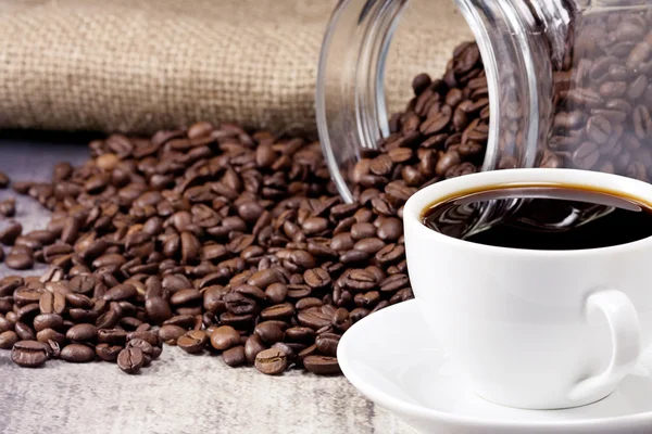 Xícara de café e jarra cheia de feijão — Fotografia de Stock