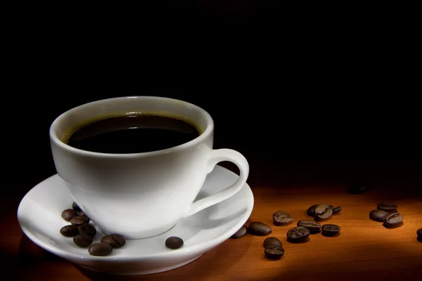 Tasse Kaffee und Bohnen auf Holztisch — Stockfoto