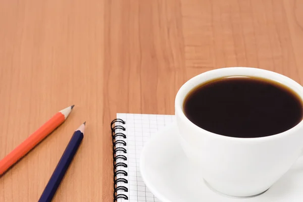 Filiżankę kawy i długopisy z notatnika — Zdjęcie stockowe