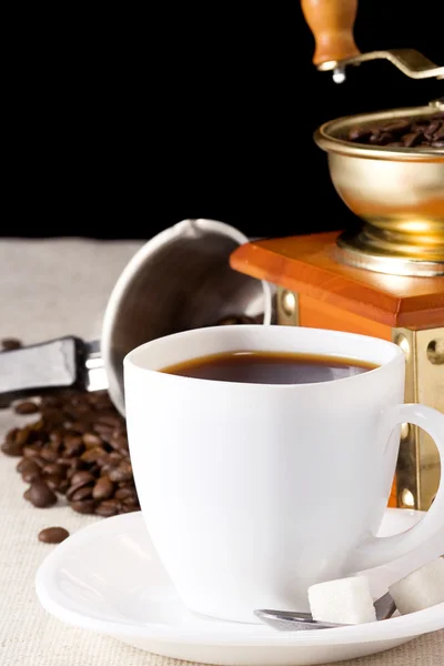 Grãos de café, xícara e moedor no saque — Fotografia de Stock