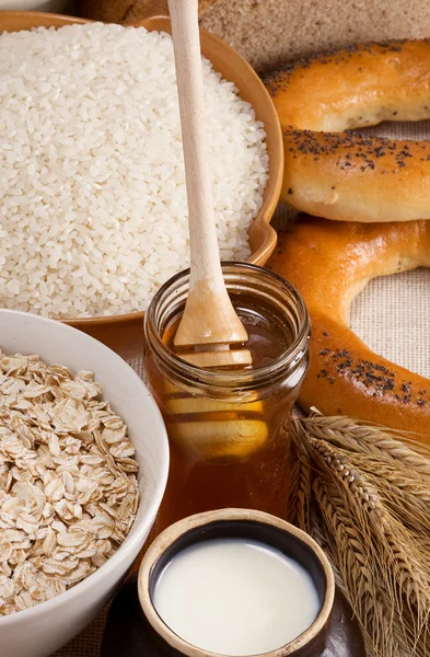 Oat, rice, honey, milk in pot and spike on sack — Stock Photo, Image