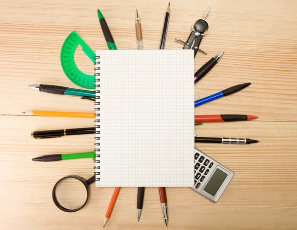 Pera, tužky a mmagnifier pod checked poznámkového bloku — Stock fotografie