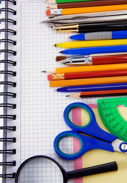 Penne, matite, lente d'ingrandimento su notebook — Foto Stock
