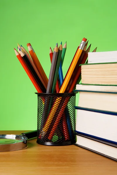 Книги, увеличитель и корзина с карандашами — стоковое фото