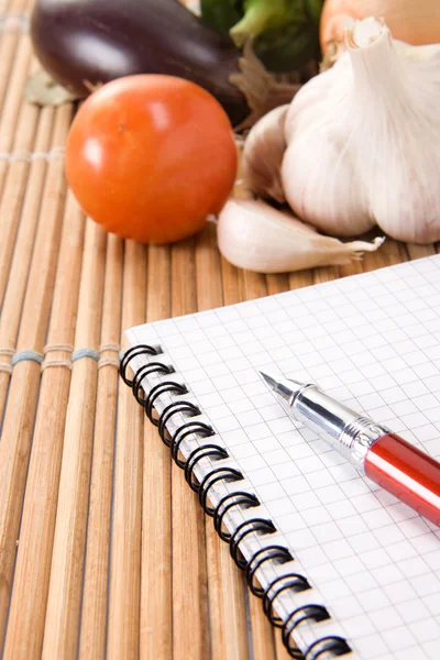Овощи и блокнот с ручкой — стоковое фото