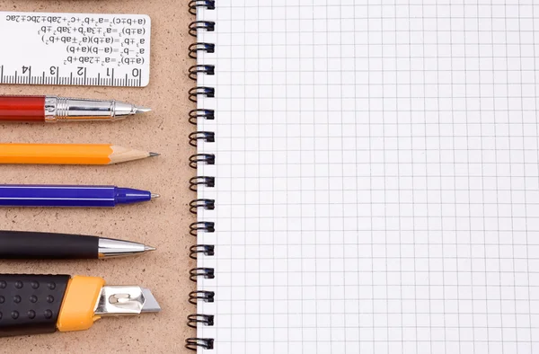 Stift, Bleistift und Papiermesser mit kariertem Notizbuch — Stockfoto