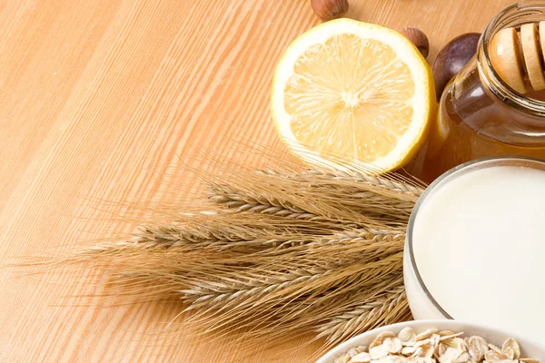 Honey, milk, oat, lemon and grain on table — Stock Photo, Image