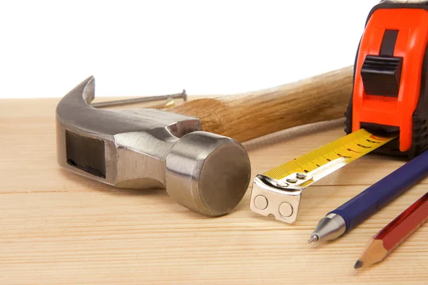 Hammer, Maßband und Bleistift auf Holzziegel — Stockfoto