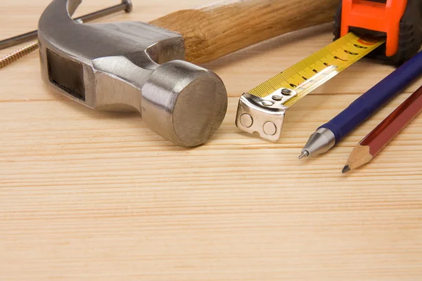 Martelo, fita métrica, prego e lápis sobre madeira — Fotografia de Stock