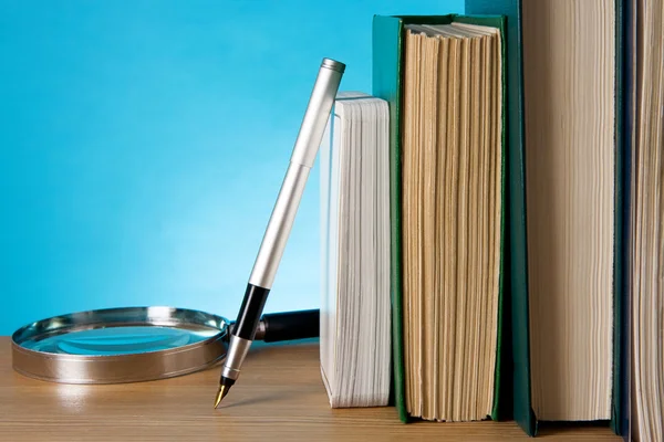 Boeken, Vergrootglas en inkt pen op hout — Stockfoto