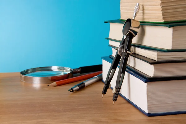 Długopis, stos książek i Lupa na stół z drewna — Zdjęcie stockowe