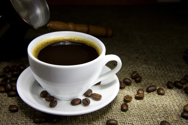 Kopp kaffe, bönor och koppar kruka på säckväv — Stockfoto