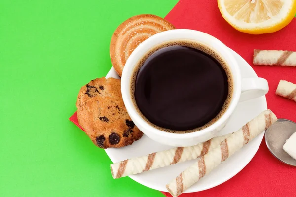 Cup of coffee and cookies on green